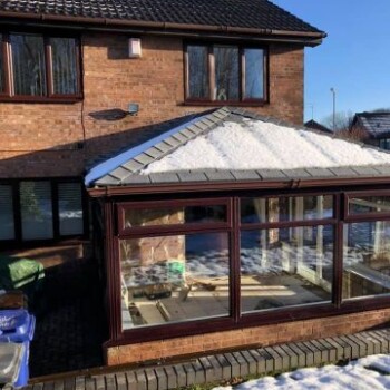 A brick house with snow on the roof and windows.