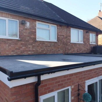 A flat roof with black rubber covering on top of brick building.
