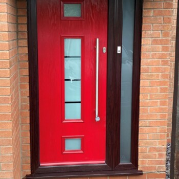 A red door with glass windows on the outside of a brick building.