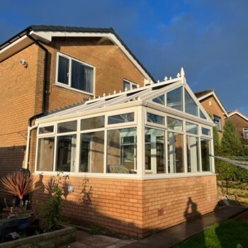 A brick house with a large glass enclosed porch.