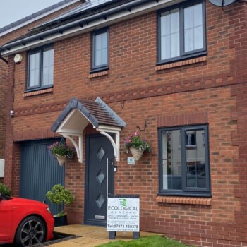A red car parked in front of a brick house.