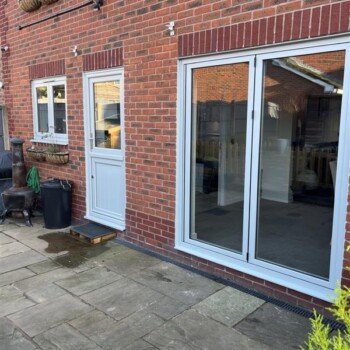 A patio with sliding glass doors and brick walls.