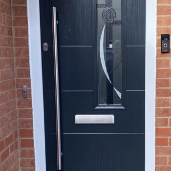 A black door with a metal handle and a glass window.