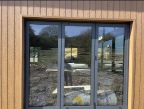 Glass doors reflecting outdoor landscape and greenery.