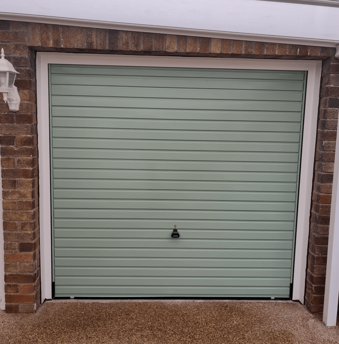 Green garage door with brick frame.