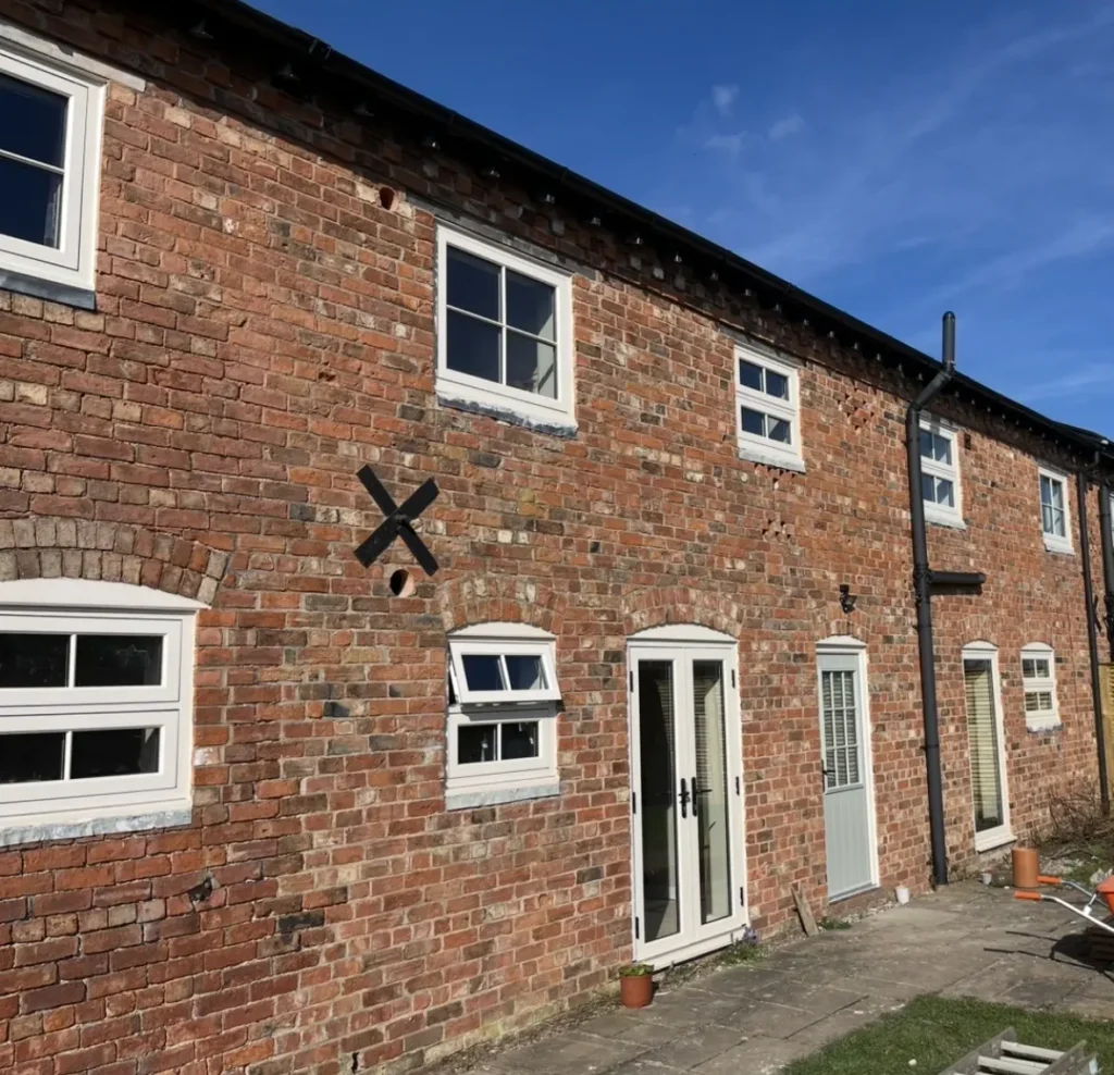 Brick house with multiple white-framed windows.